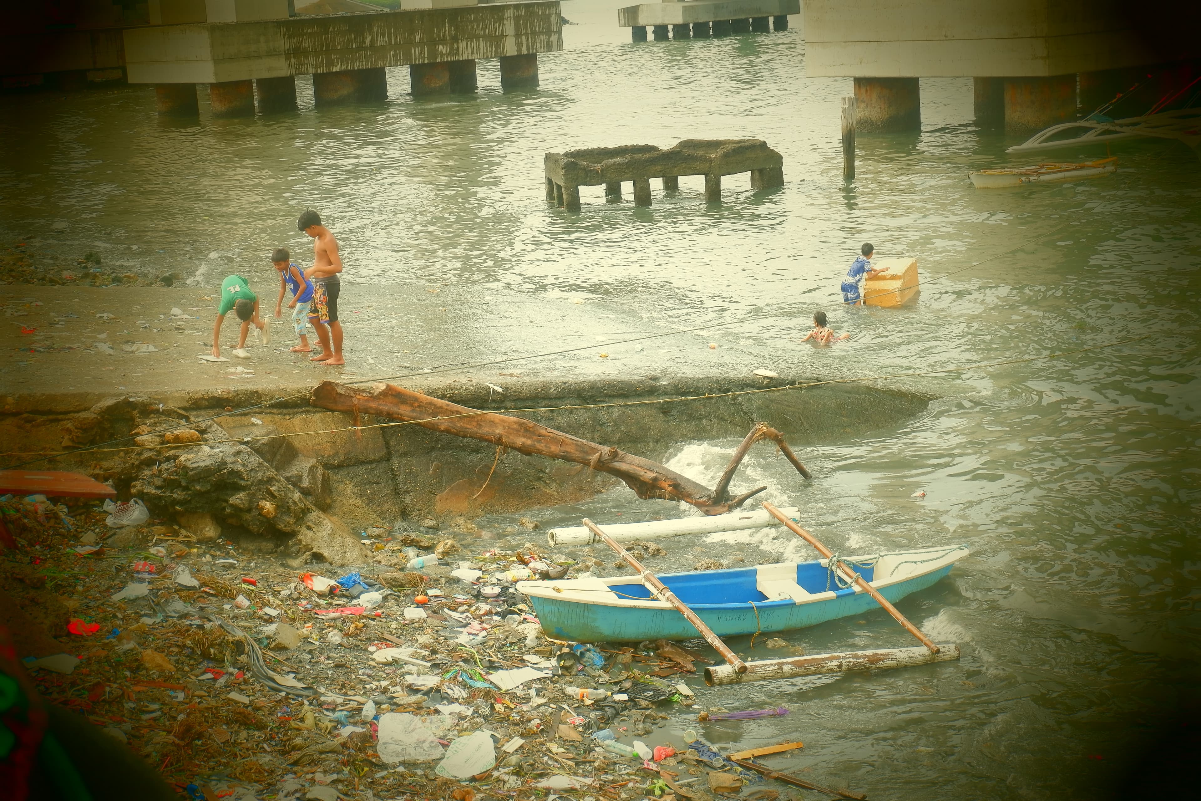 Young residents of Barangay Pasil play along the shoreline as piles of garbage begin to accumulate and rain pours.